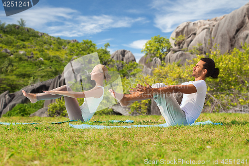 Image of couple making yoga half-boat pose outdoors