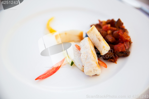 Image of white fish with stewed eggplant garnish on plate