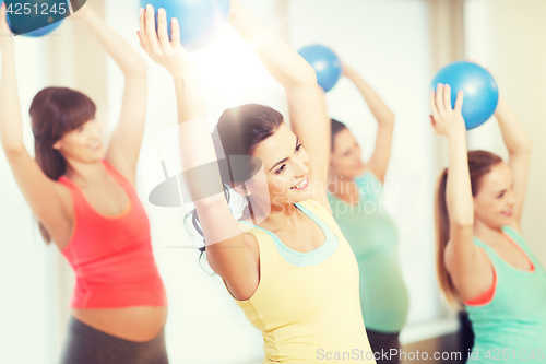 Image of happy pregnant women exercising with ball in gym