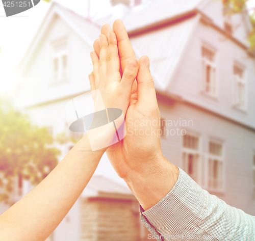 Image of father and child hands making high five over house