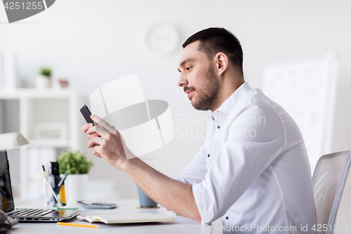 Image of businessman with smartphone and notebook at office