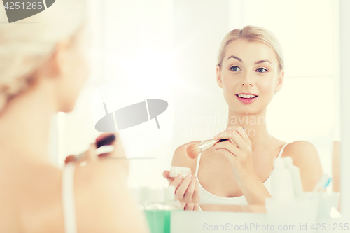 Image of woman with makeup brush and powder at bathroom