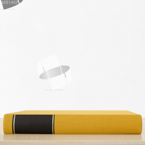 Image of Yellow book with black frame on spine on the table