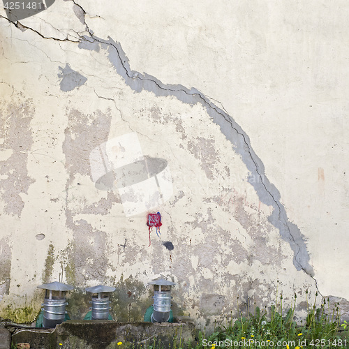 Image of abandoned cracked stucco wall with ventilation grille