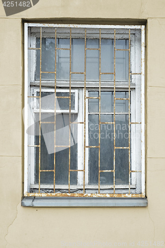 Image of abandoned grunge cracked stucco wall with window grilles