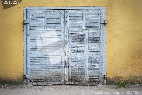 Image of grunge wooden plank door, dirty stucco wall background