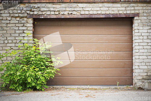 Image of Garage wooden plank door, dirty grunge brick wall