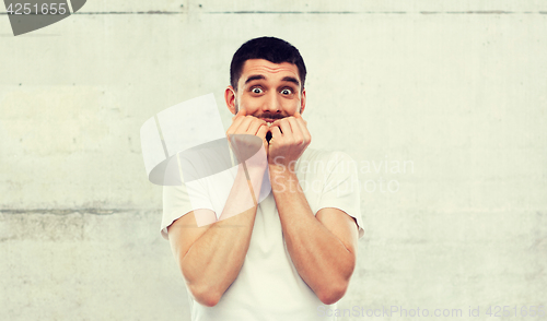 Image of scared man in white t-shirt over gray wall