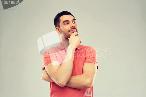 Image of man in polo t-shirt thinking over gray background