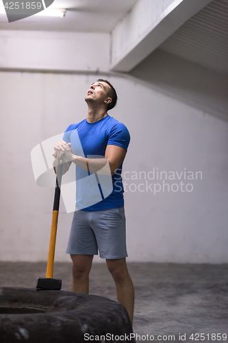 Image of man workout with hammer and tractor tire