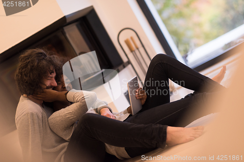 Image of multiethnic couple using tablet computer on the floor