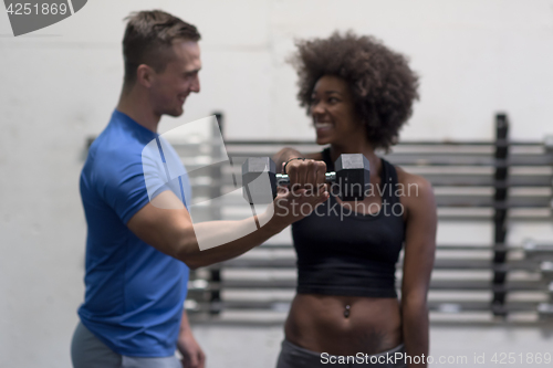 Image of black woman doing bicep curls with fitness trainer