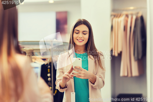 Image of woman taking mirror selfie by smartphone at store