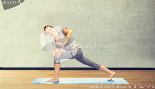 Image of woman making yoga low angle lunge pose on mat