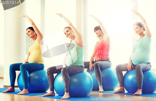 Image of happy pregnant women exercising on fitball in gym