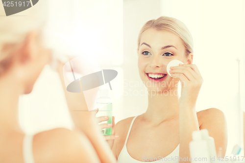 Image of young woman with lotion washing face at bathroom