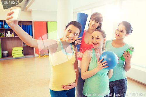 Image of pregnant women taking selfie by smartphone in gym