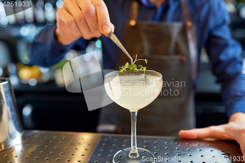 Image of bartender decorating glass of cocktail at bar