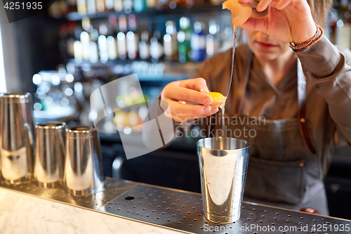 Image of bartender with shaker preparing cocktail at bar