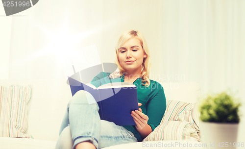 Image of smiling woman reading book at home