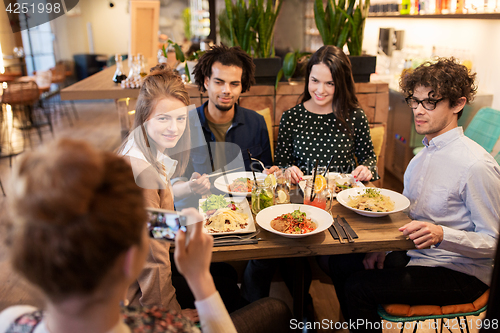 Image of friends with smartphone fotographing at restaurant