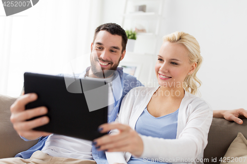 Image of smiling happy couple with tablet pc at home