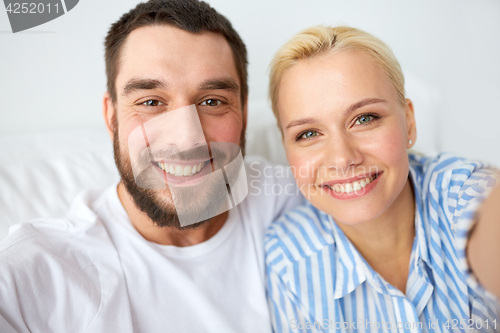 Image of happy couple taking selfie at home