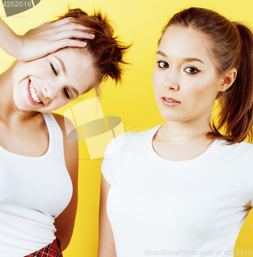 Image of lifestyle people concept: two pretty young school teenage girls having fun happy smiling on yellow background 