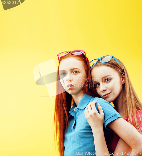 Image of lifestyle people concept: two pretty young school teenage girls having fun happy smiling on yellow background 