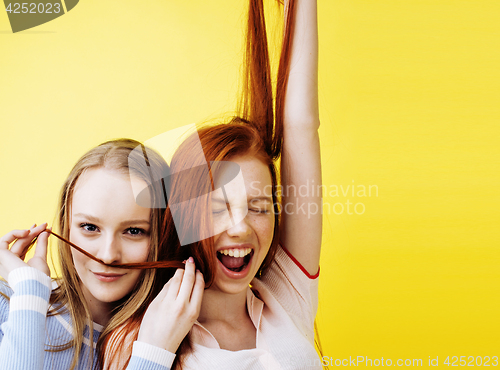 Image of lifestyle people concept: two pretty young school teenage girls having fun happy smiling on yellow background 