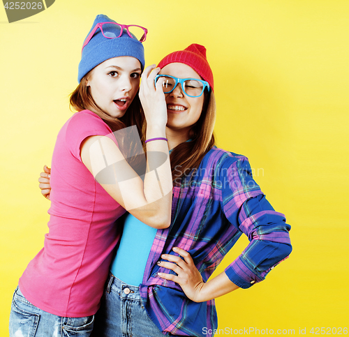 Image of lifestyle people concept: two pretty young school teenage girls having fun happy smiling on yellow background 