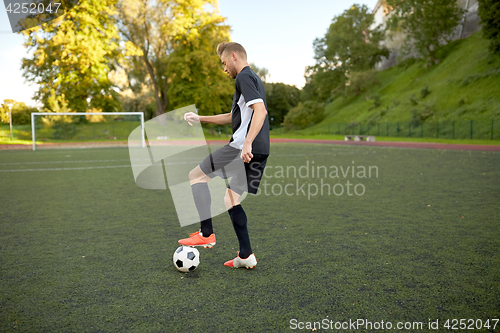 Image of soccer player playing with ball on football field