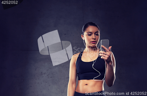 Image of woman with smartphone and earphones in gym