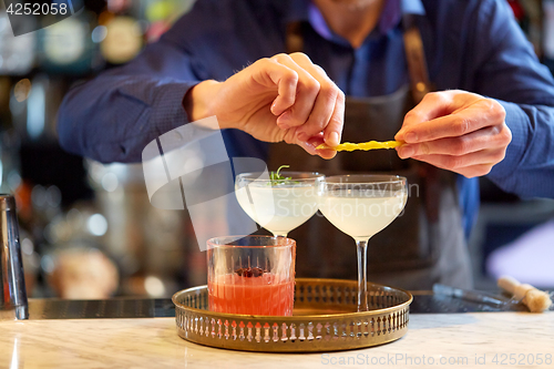 Image of bartender with glass of cocktail and lemon at bar