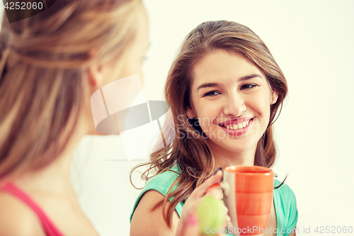 Image of happy young women drinking tea with sweets at home