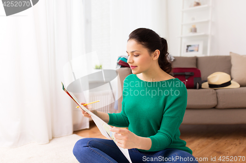 Image of happy young woman with travel map at home