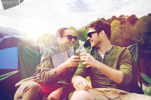 Image of happy couple clinking drinks at campsite tent