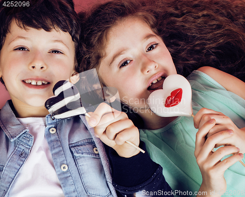 Image of lifestyle people concept: diverse nation children playing together, caucasian boy with african little girl holding candy happy smiling 