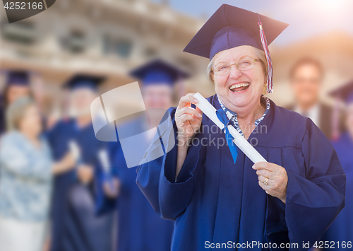 Image of Happy Senior Adult Woman In Cap and Gown At Outdoor Graduation C