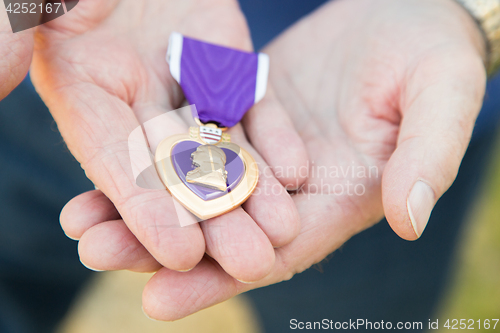 Image of Senior Man Holding The Military Purple Heart Medal In His Hands.