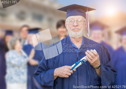 Image of Proud Senior Adult Man In Cap and Gown At Outdoor Graduation Cer