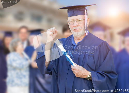 Image of Proud Senior Adult Man In Cap and Gown At Outdoor Graduation Cer