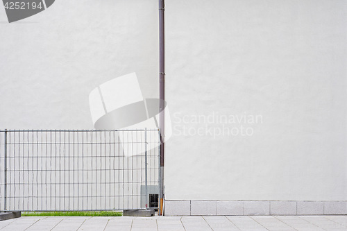 Image of white wall with water pipe, metal security fence