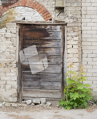 Image of wooden plank door, dirty grunge brick wall