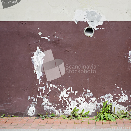 Image of abandoned cracked stucco wall with ventilation grille