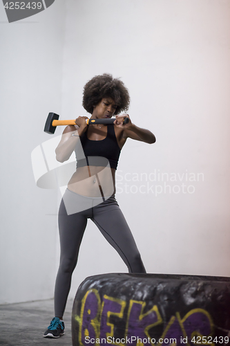 Image of black woman workout with hammer and tractor tire