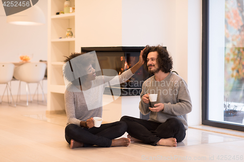 Image of multiethnic couple  in front of fireplace