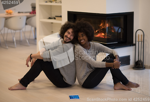 Image of multiethnic couple with tablet computer on the floor