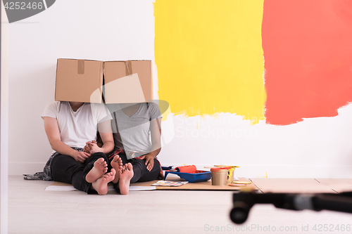 Image of young multiethnic couple playing with cardboard boxes