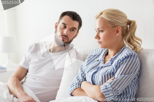 Image of unhappy couple having conflict in bed at home